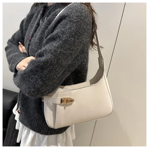 Close-up of beige hobo bag with gold metal twist lock buckle on a grey sweater