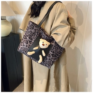 Close-up of leopard print tote bag with a plush bear detail on a black leather pocket
