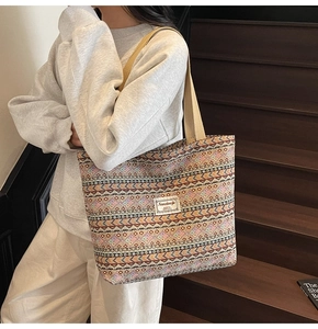 Ethnic tote bag with geometric patterns shown on model by wooden stairs