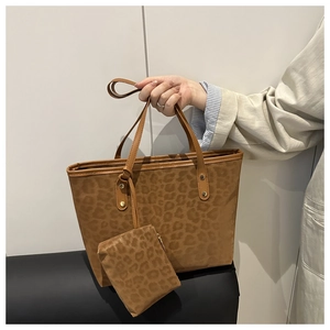 Detail of leopard print tote bag showing suede texture, matching pouch, and gold rivets