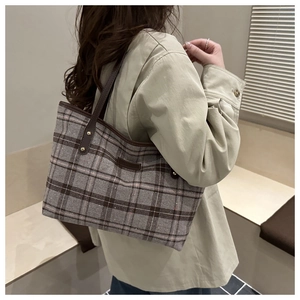 Close-up of retro plaid tweed fabric and brown leather handle on a large tote bag