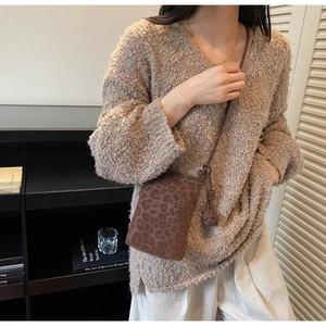 Close-up of leopard print phone bag with knotted leather strap on brown sweater