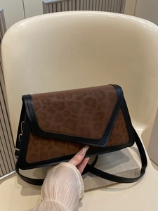 Retro leopard print crossbody bag with black leather trim on a minimalist chair