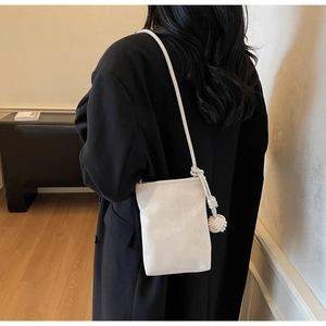 Close-up of cream crossbody bag featuring oversized knot accents and minimalist leather design
