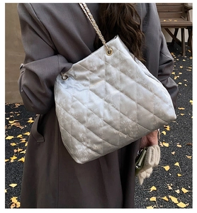 Detailansicht der silbernen Stepptasche mit goldener Kette an der Schulter