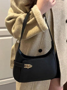 Chic black half-moon underarm bag with gold buckle on elegant winter wool coat