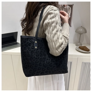 Detailed shot of large leopard print tote bag with black straps and gold rivets on a model