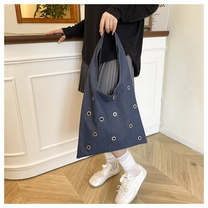 Gros plan détaillé sur le tissu denim et les oeillets métalliques du grand sac fourre-tout