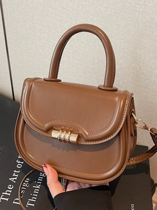 Brown retro saddle bag with gold metal lock and top handle shown in a studio setting