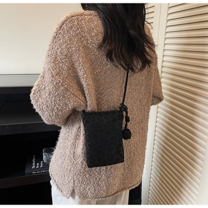 Back view of model wearing a black leopard print mini crossbody bag with rope strap