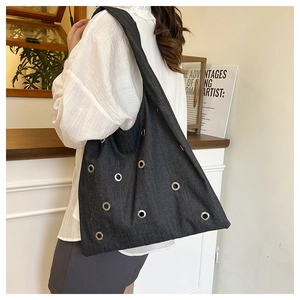 Détail du grand sac cabas en denim gris foncé avec œillets métalliques et bandoulière large