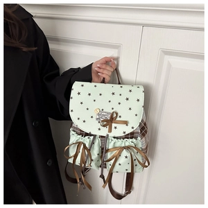 Detail of mint green star pattern backpack with brown plaid trim and ribbon bows