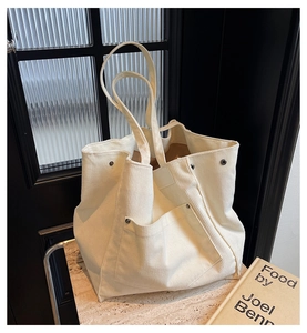 Close-up of cream corduroy tote bag showing vertical texture and silver rivet detail