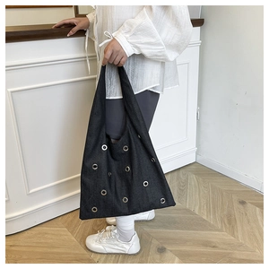 Vue détaillée du sac cabas en denim noir avec œillets métalliques argentés et rivets