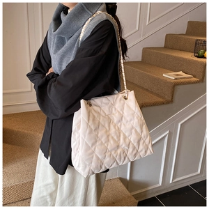 Schicke Stepptasche mit goldener Kette und cremefarbenem Lederfinish am Modell