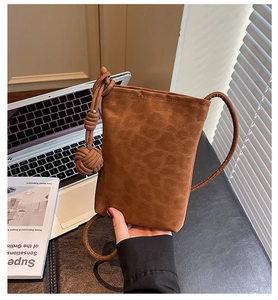 Detail of a brown suede mini crossbody bag featuring a unique oversized knotted tassel cord