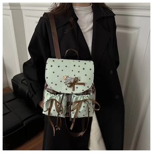 Detail of light green canvas backpack with star print, bow ribbon, and checkered side panel