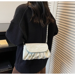 Close-up of pleated cloud texture and silver chain strap on light beige shoulder bag