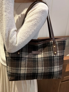 Plaid wool tote bag with brown leather handles worn by model in autumn style