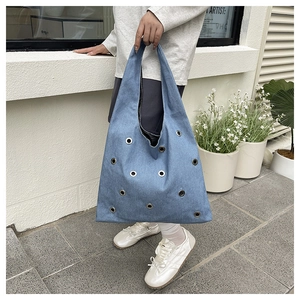 Détail du sac cabas en denim bleu avec œillets métalliques et design décontracté