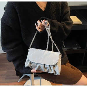 Silver pleated shoulder bag with metallic chain strap shown in a lifestyle setting