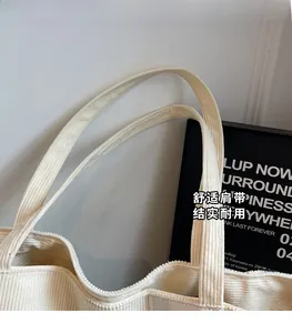 Detailed close-up of wide shoulder straps and beige corduroy texture on the tote bag