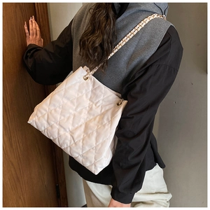 Detailansicht einer weißen Stepptasche mit goldener Kette getragen von einem Model für den Alltag