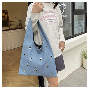 Vue détaillée du sac cabas en denim bleu clair avec des œillets métalliques argentés