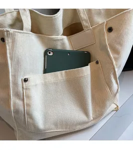 Detail view of large corduroy tote bag with front pocket and metal rivet accents