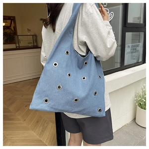 Détail du sac cabas en jean bleu avec œillets métalliques et grande capacité de rangement