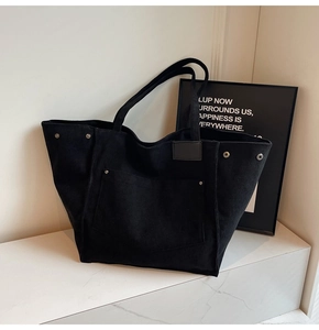 Detailed texture of black corduroy tote bag showing vertical ribs and silver rivets