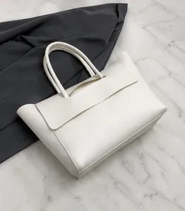 Detalle del bolso tote de cuero PU blanco que muestra la textura lisa y el cierre de solapa