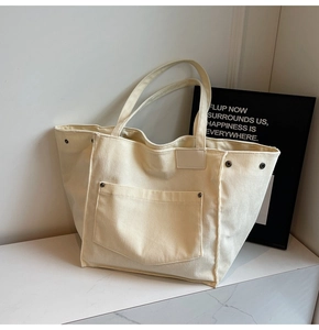 Detailed macro view of beige corduroy tote bag showing ribbed texture and metal rivets