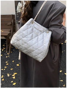 Seitenansicht der silbernen Stepptasche mit Kettenriemen am Model in Herbstlandschaft
