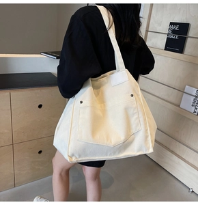 Detailed texture of off-white corduroy tote bag with front pocket and rivet details