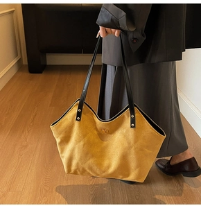 Detail of yellow quilted suede tote bag with gold metal clasp and leather handles