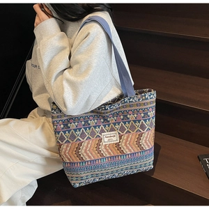 Detailed shot of tribal print tote bag with geometric patterns and blue shoulder strap