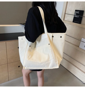 Detail of off-white corduroy tote bag featuring vertical texture and rivet front pocket