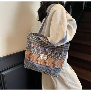 Detail of bohemian woven tote bag with colorful ethnic patterns and long purple strap