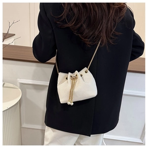 Detail of cream corduroy bucket bag with gold chain strap and pearl drawstring accents