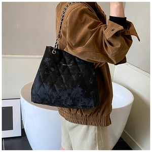 Detailaufnahme der schwarzen Stepptasche mit goldener Metallkette und Samttextur