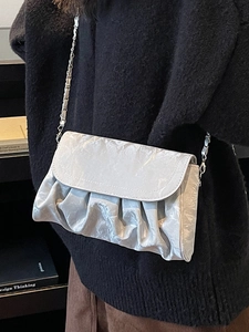Silver pleated cloud shoulder bag with metallic chain strap worn by a model