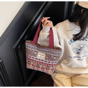 Detailed close-up of colorful ethnic patterned tote bag with sturdy red handles