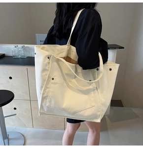 Detail of off-white corduroy tote bag featuring a front pocket and metal buckle detail