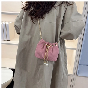 Detail of pink corduroy drawstring bucket bag with pearl charms and gold chain strap