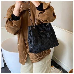 Detail der schwarzen gesteppten Ledertasche mit goldenem Logo und Kettenriemen