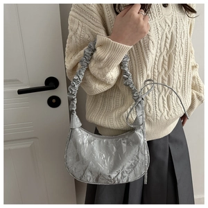Detail of silver metallic pleated handbag with scrunchie handle and stylish ribbon detail