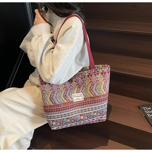 Close-up of large jacquard tote bag with vintage texture and red handles on stairs