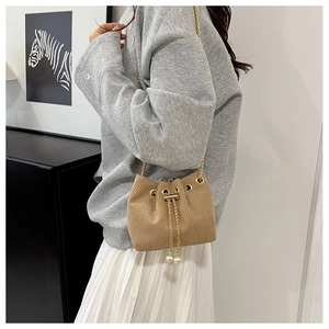 Detail of light brown corduroy bucket bag with pearl drawstring and gold chain strap