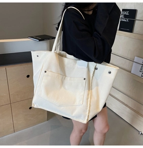 Detail of corduroy canvas tote bag showing vertical texture, metal studs and large pocket